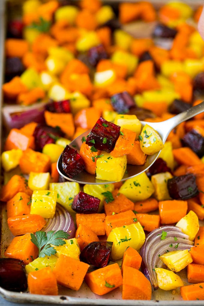 Roasted Root Vegetables Recipe | Roasted Sweet Potatoes | Roasted Beets | Roasted Carrots #carrots #beets #vegetables #sweetpotatoes #fall #parsnips #sidedish #jonep #cleaneating #healthy A spoon serving up a portion of roasted vegetables.