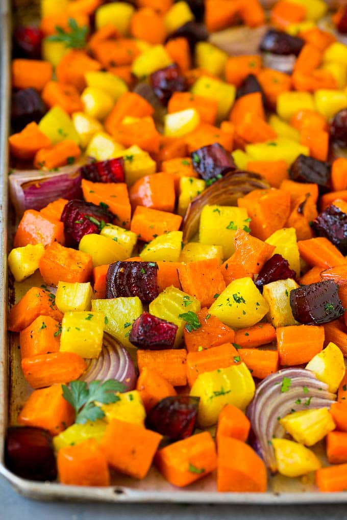 Roasted Root Vegetables Recipe | Roasted Sweet Potatoes | Roasted Beets | Roasted Carrots #carrots #beets #vegetables #sweetpotatoes #fall #parsnips #sidedish #jonep #cleaneating #healthy Roasted root vegetables on a sheet pan, topped with chopped parsley.