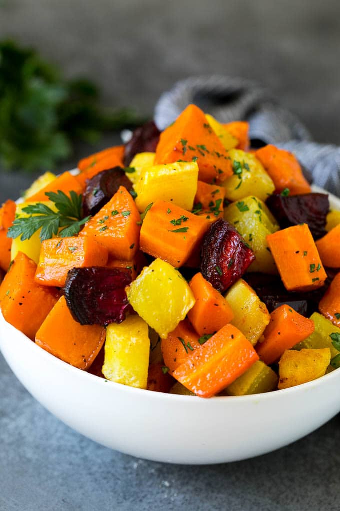 Roasted Root Vegetables Recipe | Roasted Sweet Potatoes | Roasted Beets | Roasted Carrots #carrots #beets #vegetables #sweetpotatoes #fall #parsnips #sidedish #jonep #cleaneating #healthy A bowl of diced roasted root vegetables topped with parsley.