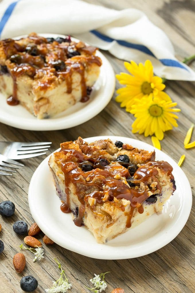 Blueberry Bread Pudding Recipe | Blueberry Bread Pudding | Easy Bread Pudding #blueberry #breadpudding #dessert #jonep Two pieces of blueberry bread pudding on plates with salted caramel on top.