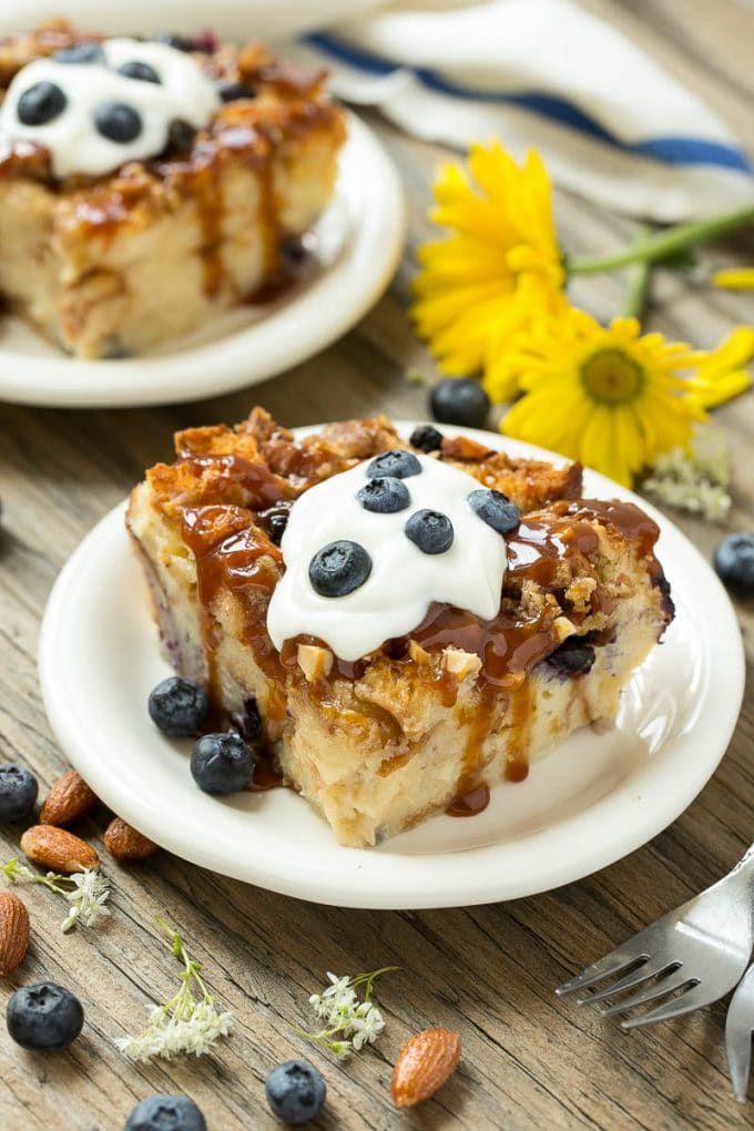 Blueberry Bread Pudding Recipe | Blueberry Bread Pudding | Easy Bread Pudding #blueberry #breadpudding #dessert #jonep Slices of bread pudding on plates, topped with caramel and fresh berries.