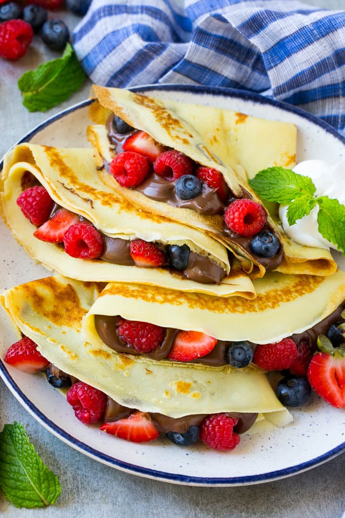Nutella Crepes Recipe | Easy Crepes Recipe | Blender Crepes | Berry Crepes #crepes #nutella #nutellacrepes #blendercrepes #breakfast #jonep A platter of crepes served with whipped cream.