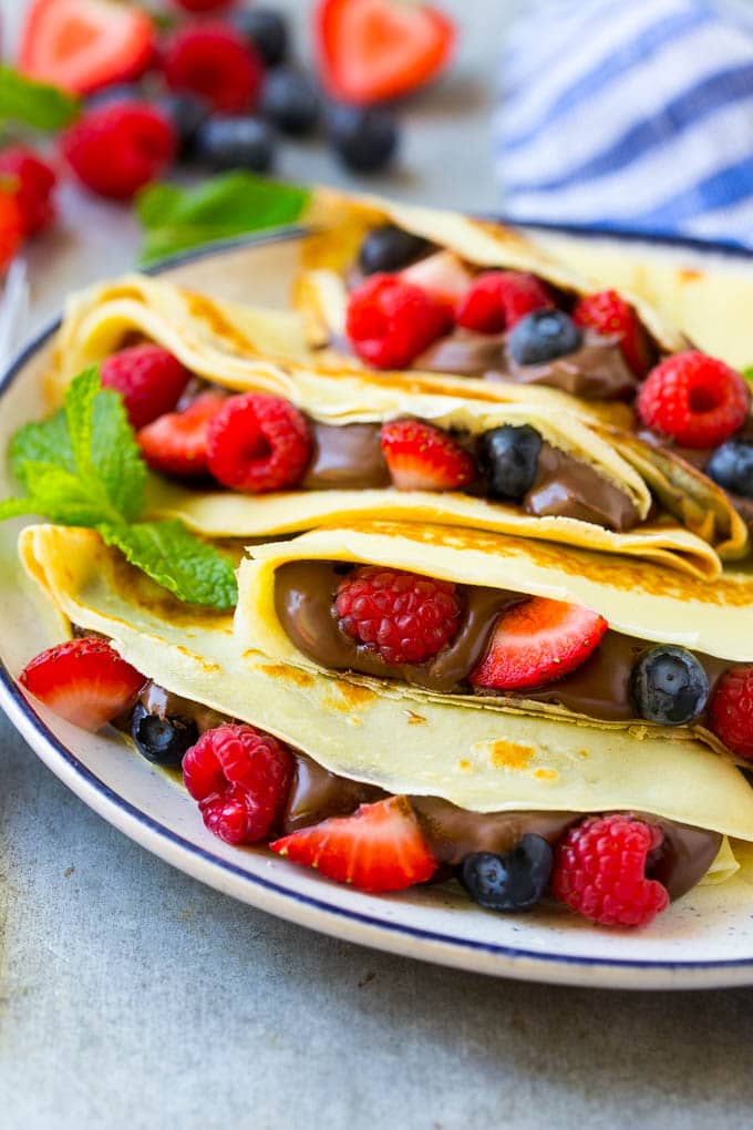 Nutella Crepes Recipe | Easy Crepes Recipe | Blender Crepes | Berry Crepes #crepes #nutella #nutellacrepes #blendercrepes #breakfast #jonep A plate of Nutella crepes with strawberries, blueberries and raspberries.