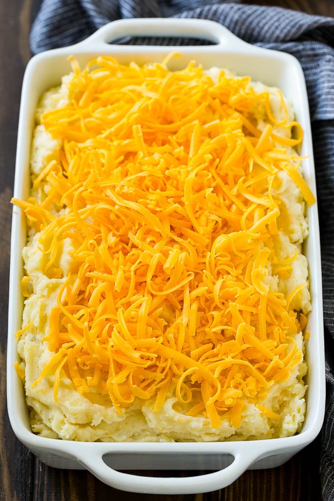 Loaded Mashed Potato Casserole Recipe | Loaded Potatoes | Bacon Mashed Potatoes | Thanksgiving Mashed Potatoes #potatoes #bacon #cheese #casserole #Thanksgiving #dinner #jonep Mashed potatoes in a casserole dish, topped with shredded cheese.
