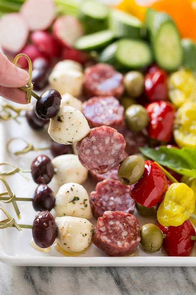 Antipasto Skewers Recipe | Easy Antipasto | Best Antipasto #antipasto #skewers #appetizer #jonep A hand holding up a skewer of salami, cheese and olives.