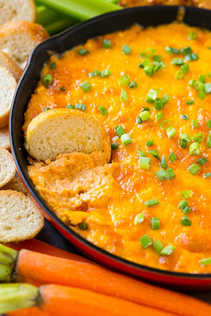 Buffalo Ranch Chicken Dip | Buffalo Chicken Dip | Baked Buffalo Dip | Cheesy Buffalo Dip #buffalowings #buffalochicken #dip #lowcarb #appetizer #jonep Buffalo ranch chicken dip with a baguette slice in it.