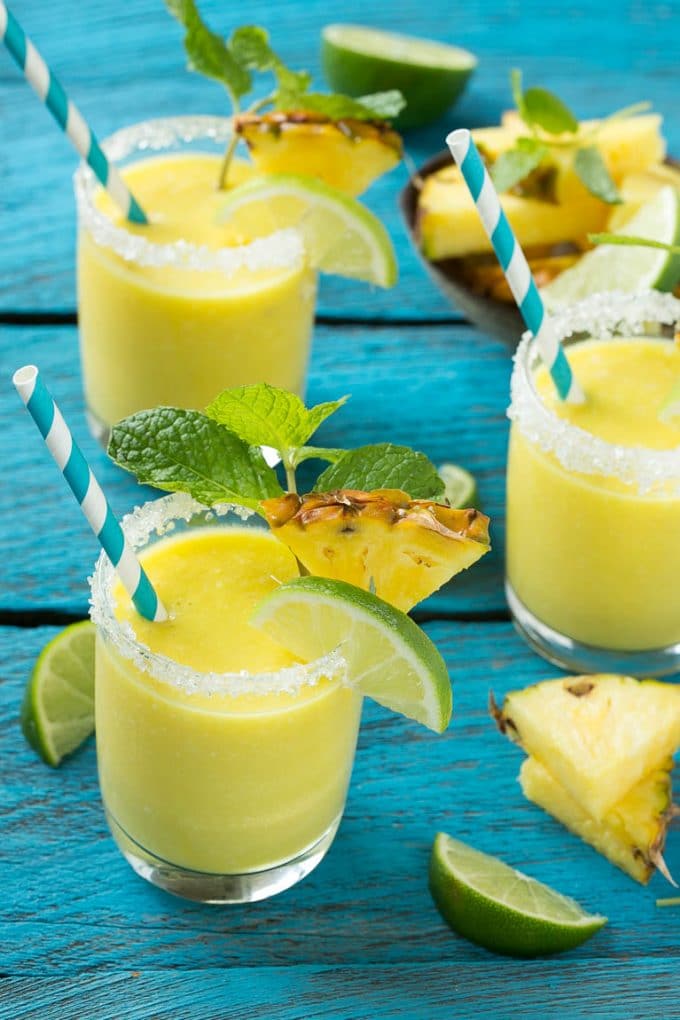Pineapple Coconut Smoothie Recipe |Tropical Smoothie | Pineapple Smoothie #smoothie #pineapple #coconut #healthy #cleaneating #jonep Glasses of pineapple coconut smoothie garnished with limes and mint.