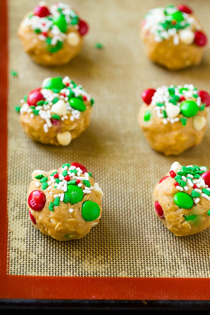 Christmas Monster Cookies Recipe | Oatmeal Cookies | Peanut Butter Cookies | M&M's Cookies #baking #cookies #dessert #peanutbutter #chocolate #jonep #christmas #sprinkles Balls of cookie dough on a baking sheet.