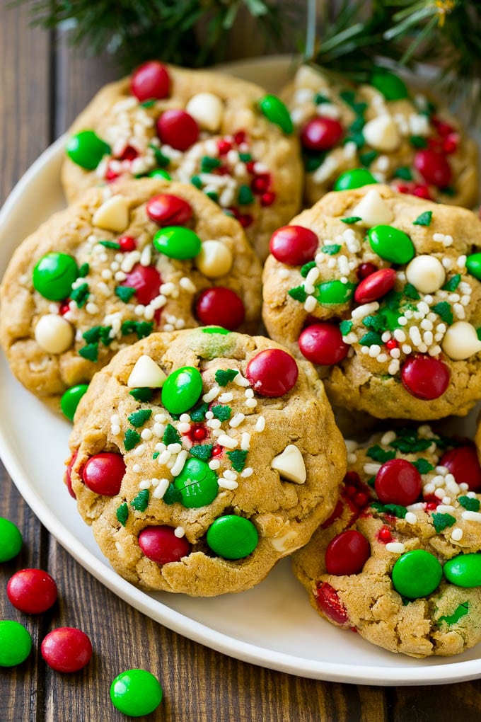 Christmas Monster Cookies Recipe | Oatmeal Cookies | Peanut Butter Cookies | M&M's Cookies #baking #cookies #dessert #peanutbutter #chocolate #jonep #christmas #sprinkles A plate of Christmas monster cookies which are decorated with M&M's, white chocolate and sprinkles.