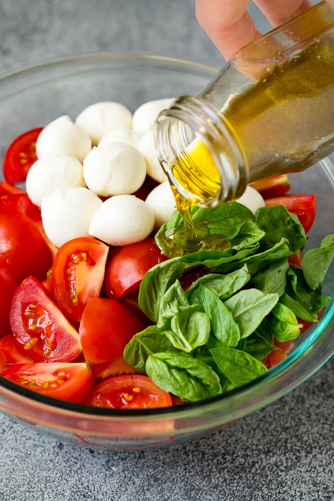 Caprese Salad Recipe | Tomato Salad #salad #tomato #mozzarella #cheese #basil #caprese #summer #jonep Olive oil being poured over tomatoes, mozzarella and basil leaves.