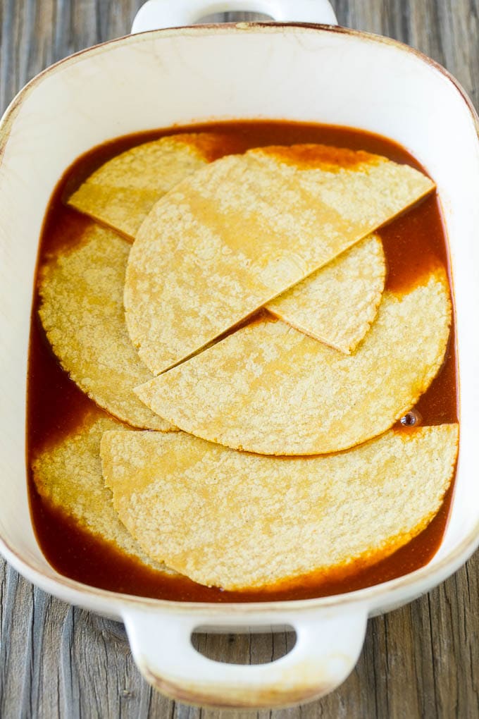 Chicken Enchilada Casserole Recipe | Chicken Enchiladas | Easy Casserole Recipe | Enchilada Casserole #chicken #casserole #enchiladas #cheese #beans #dinner #jonep Corn tortillas and enchilada sauce in a casserole dish.