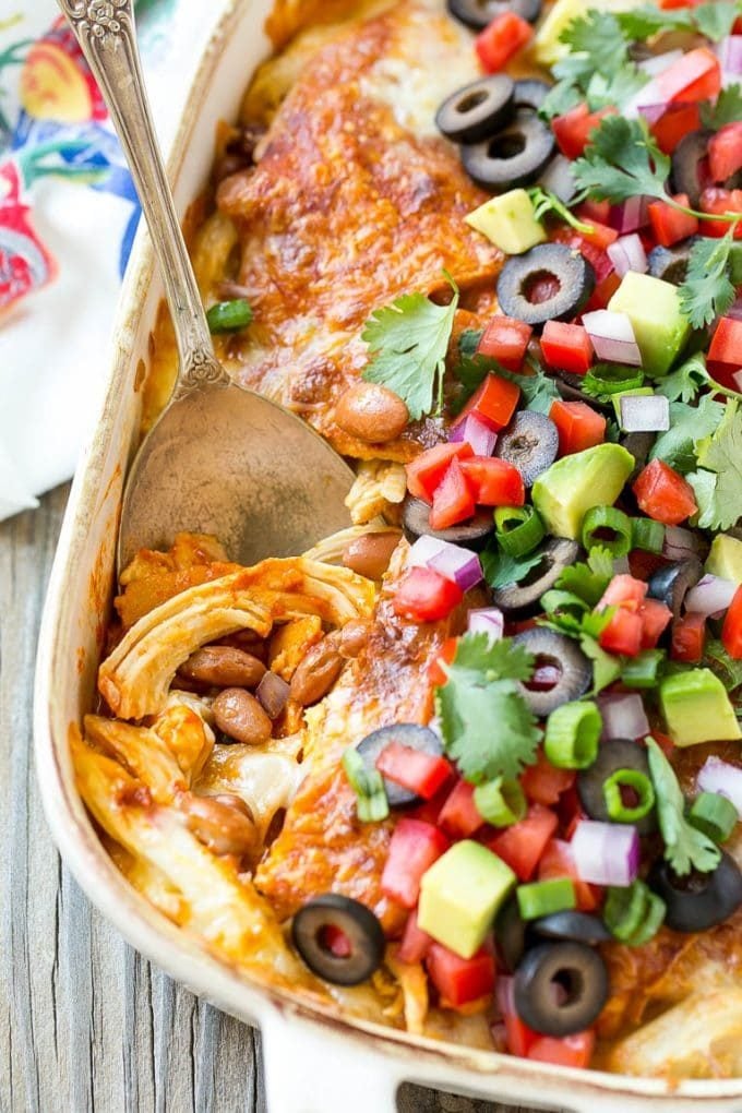 Chicken Enchilada Casserole Recipe | Chicken Enchiladas | Easy Casserole Recipe | Enchilada Casserole #chicken #casserole #enchiladas #cheese #beans #dinner #jonep A chicken enchilada casserole with a serving spoon in it.
