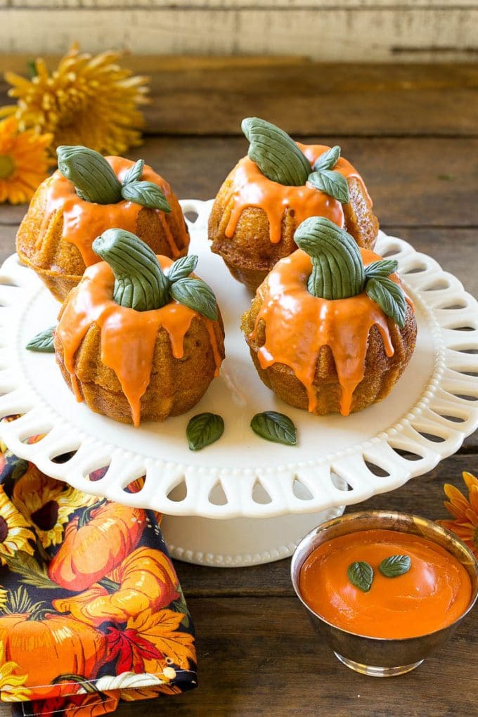 Pumpkin Spice Cake Recipe | Pumpkin Cake | Easy Pumpkin Cake | Thanksgiving Dessert #thanksgiving #pumpkin #cake #pumpkincake #spicecake #dessert #jonep #holiday Pumpkin spice cake topped with orange glaze and fondant decorations on a serving platter.
