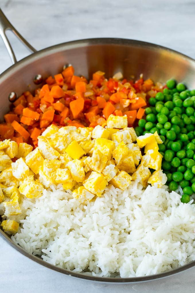 Vegetables, scrambled egg, rice and peas in a frying pan.