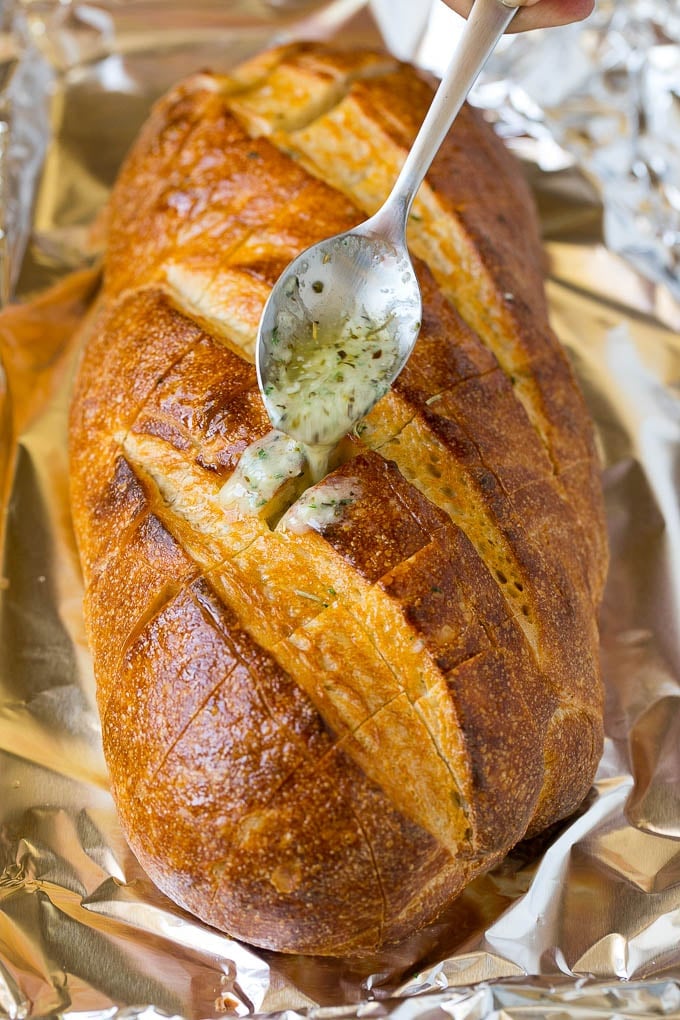 Pull Apart Bread | Garlic Bread | Cheese Bread #bread #garlic #cheese #sidedish #appetizer #jonep A spoon drizzling garlic butter over a loaf of bread.