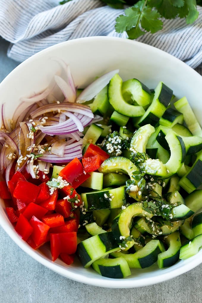 Asian Cucumber Salad Recipe | Sesame Cucumber Salad | Cucumber Salad | Healthy Salad | Healthy Cucumber Recipe #cucumber #cucumbersalad #salad #sidedish #jonep Sliced cucumbers, red peppers and onions with dressing.