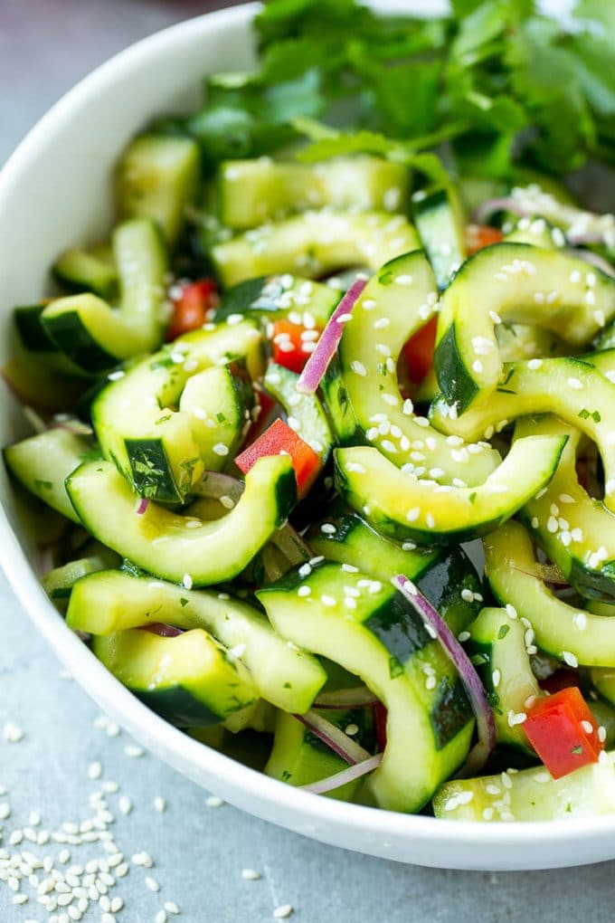 Asian Cucumber Salad Recipe | Sesame Cucumber Salad | Cucumber Salad | Healthy Salad | Healthy Cucumber Recipe #cucumber #cucumbersalad #salad #sidedish #jonep A bowl of Asian cucumber salad with dressing and sesame seeds on top.