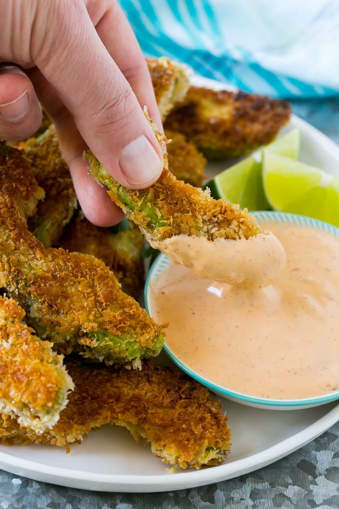 Avocado Fries Recipe | Fried Avocado | Avocado Fritters #avocado #appetizer #snack #jonep A hand dipping an avocado fry into sauce.