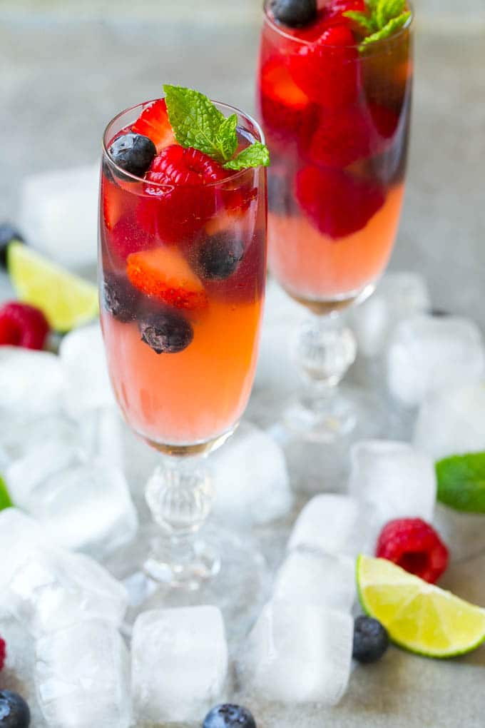 Berry Champagne Punch Recipe | Champagne Cocktail | Lime Cocktail | Berry Punch | Champagne Recipe #champagne #punch #berries #drink #jonep Two champagne flutes filled with berry champagne punch garnished with berries.