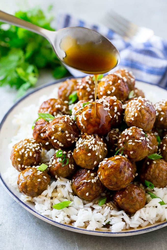 Teriyaki Meatballs Recipe | Asian Meatballs Recipe | Easy Meatball Recipe | Appetizer Meatballs #meatballs #teriyaki #beef #rice #dinner #jonep Teriyaki sauce spooned over a pile of meatballs on a bed of rice.