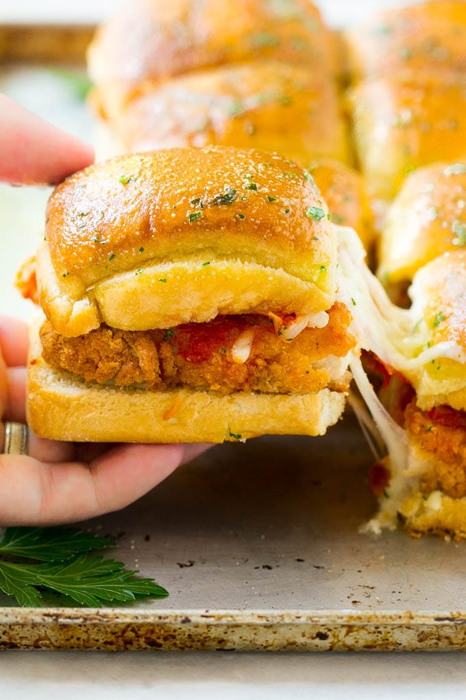 Chicken Parmesan Sliders | Chicken Parmesan Sandwich Recipe | Slider Sandwich Recipe #sliders #chickenparm #chickenparmesan #chickenparmesansliders #dinner #appetizer #jonep A crispy chicken parmesan slider being pulled away by a hand.