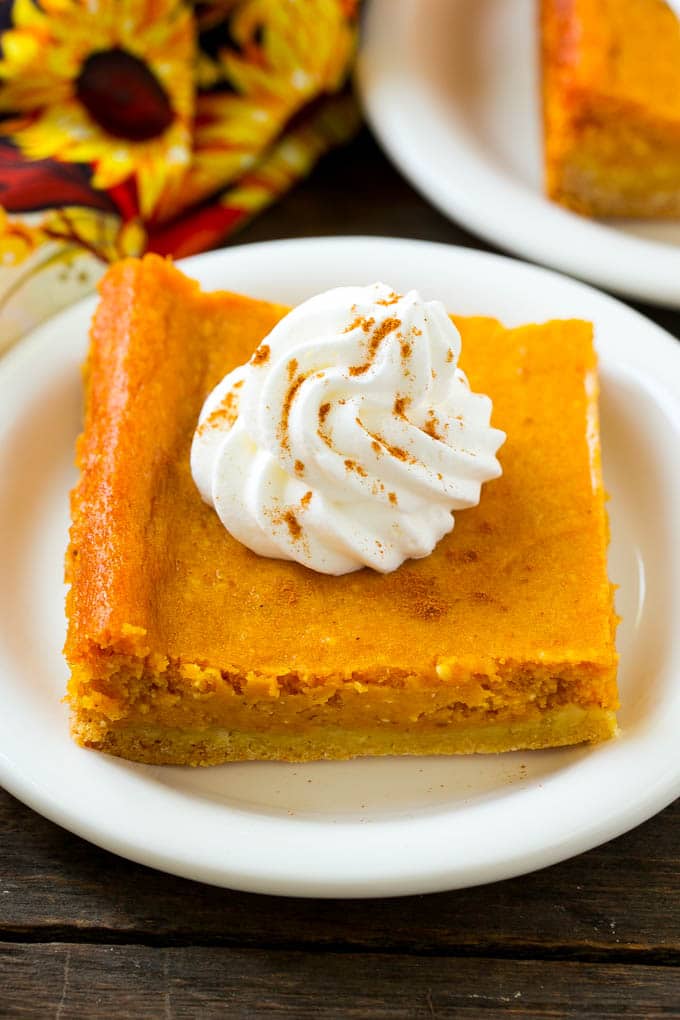 Pumpkin Gooey Butter Cake Recipe | Pumpkin Cake Recipe | Gooey Butter Cake | Pumpkin Dessert | Thanksgiving Dessert #pumpkin #cake #pumpkincake #gooeybuttercake #dessert #jonep A slice of pumpkin gooey butter cake topped with whipped cream.