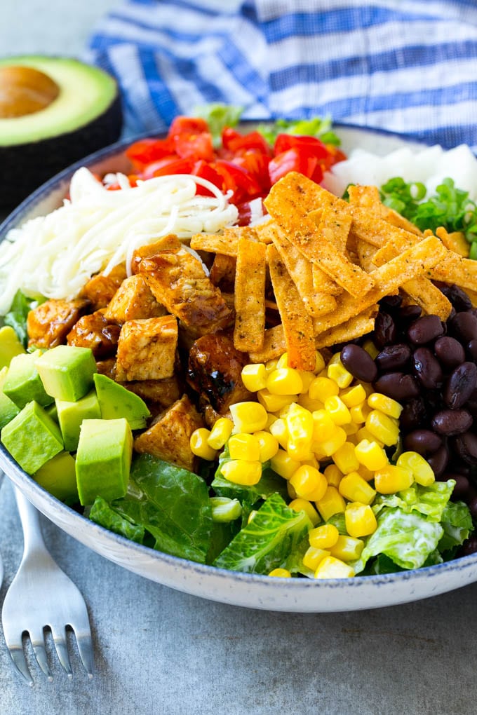 BBQ Chicken Salad Recipe | Chopped BBQ Chicken Salad | CPK Copycat Recipe | California Pizza Kitchen Copycat Recipe | Chicken Ranch Salad #copycat #CPK #BBQchicken #chicken #salad #dinner #jonep A bowl of salad topped with chicken, tortilla strips, black beans, jiacama, avocado and tomatoes.