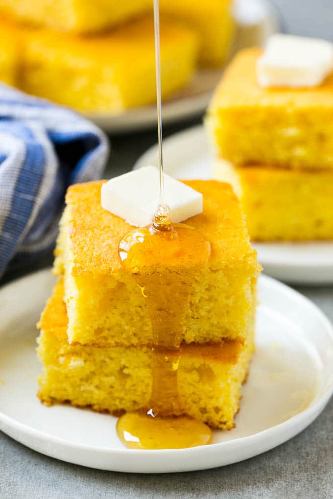Honey Cornbread Recipe | Buttermilk Cornbread | Easy Cornbread | Homemade Cornbread | Cast Iron Cornbread #cornbread #honey #buttermilk #bread #jonep A stack of cornbread topped with butter and honey