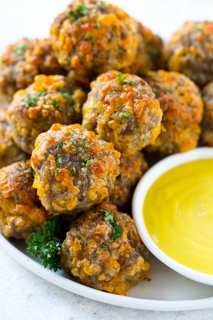 Sausage Cheese Balls Recipe | Sausage Balls Recipe | Bisquick Sausage Balls #sausage #sausageballs #balls #appetizer #cheeseballs #jonep A pile of sausage cheese balls with a side of honey mustard.