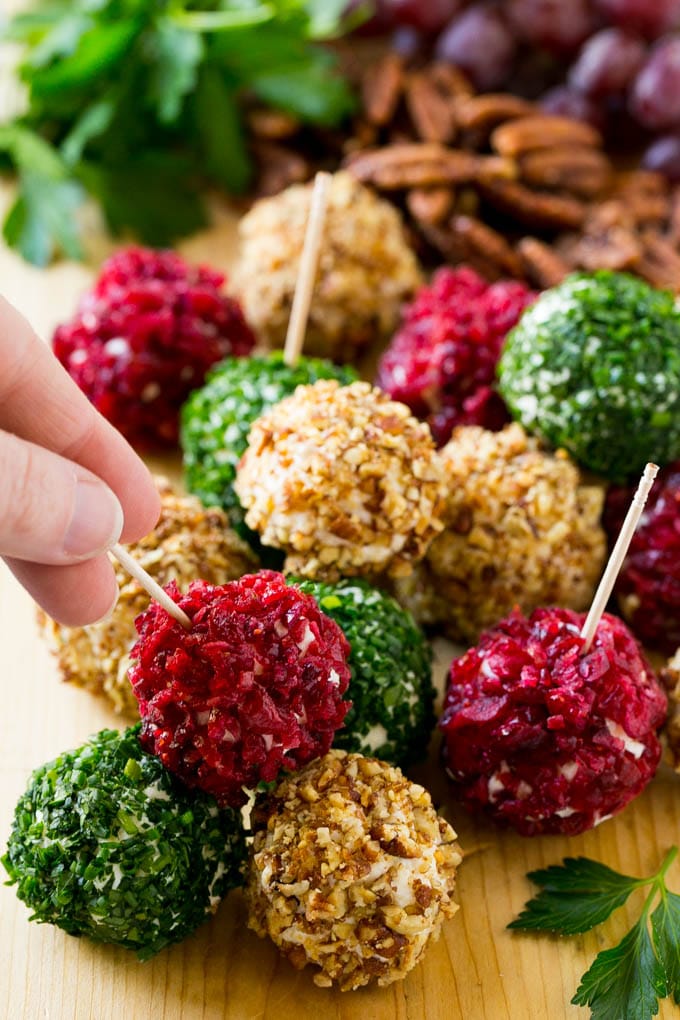 Cheese Ball Bites Recipe | Holiday Cheese Ball Recipe | Pecan Cheese Ball | Cranberry Cheese Ball | Mini Cheese Balls #cheeseball #cheese #appetizer #jonep A hand reaching for an appetizer crusted in dried craberries.