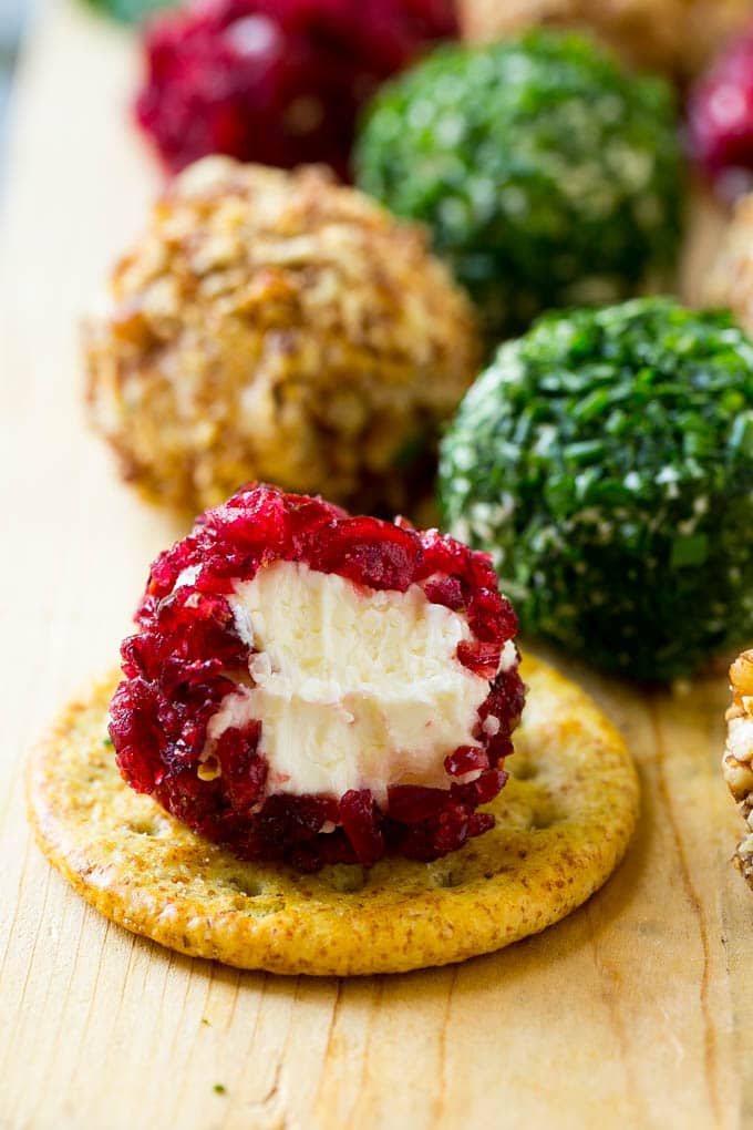 Cheese Ball Bites Recipe | Holiday Cheese Ball Recipe | Pecan Cheese Ball | Cranberry Cheese Ball | Mini Cheese Balls #cheeseball #cheese #appetizer #jonep A cranberry crusted ball of cheese on a cracker.