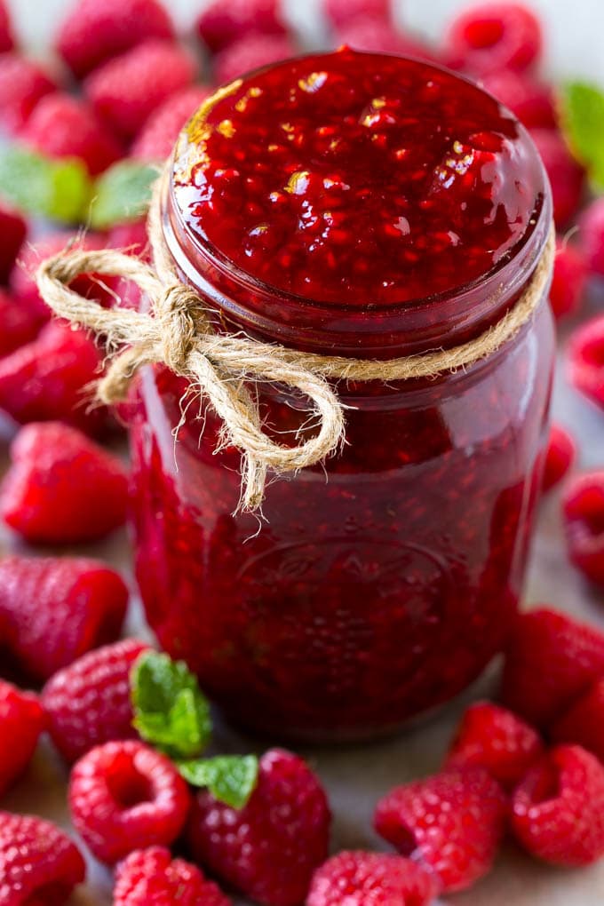 Raspberry Sauce Recipe | Homemade Raspberry Sauce | Raspberry Recipe #raspberries #dessert #jonep A jar of homemade raspberry sauce surrounded by fresh raspberries.