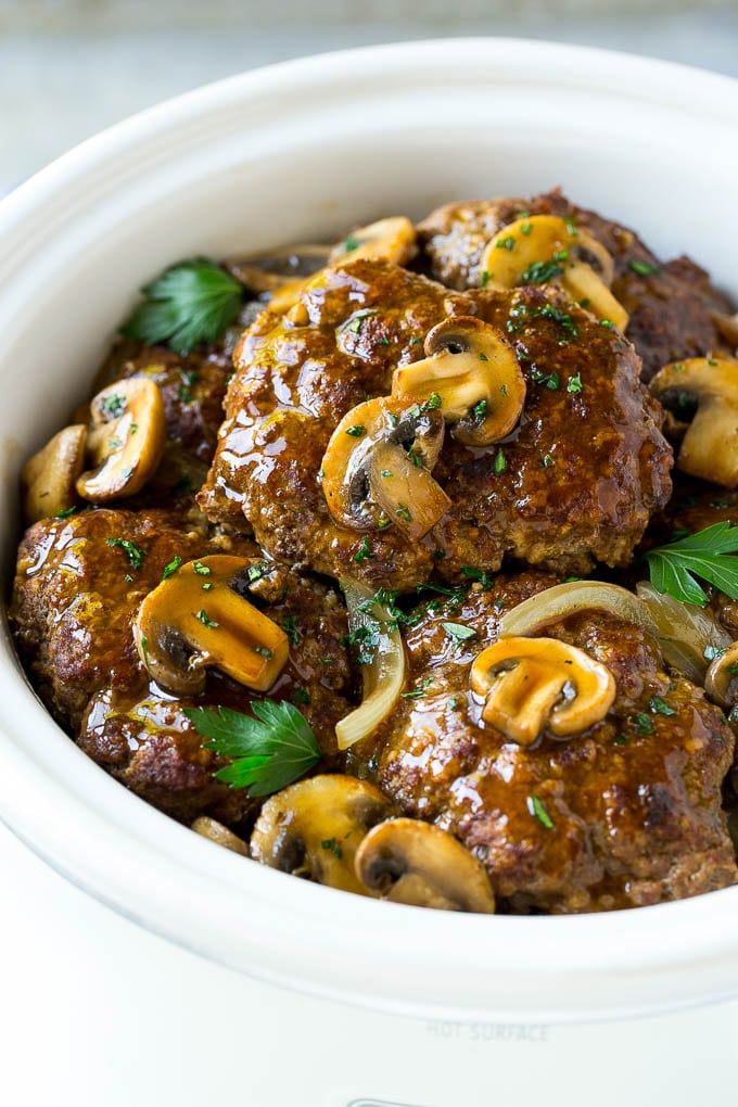 Slow Cooker Salisbury Steak Recipe | Homemade Salisbury Steak | Salisbury Steak from Scratch #steak #beef #salisbury #salisburysteak #slowcooker #crockpot #dinner #jonep A crock pot with hamburger patties, cooked mushrooms and gravy.