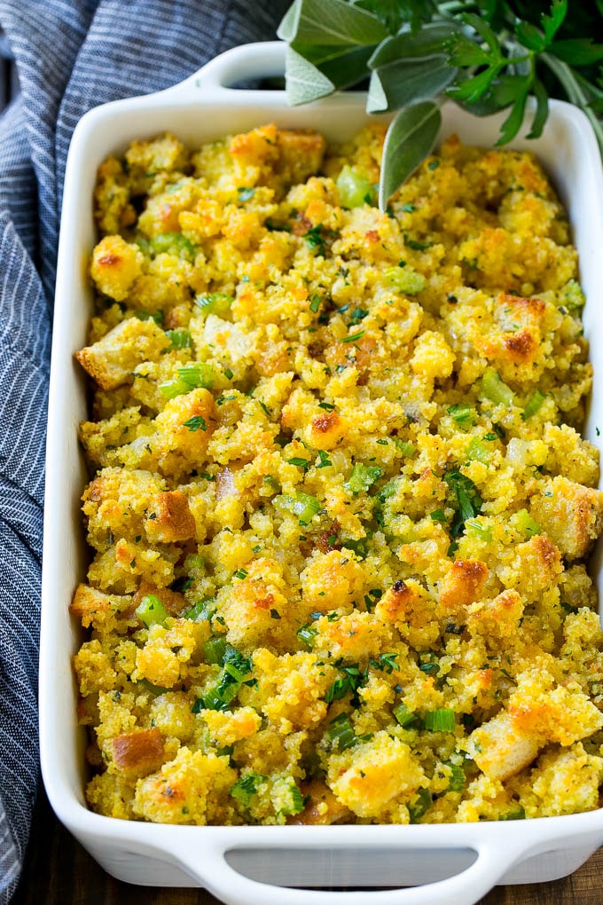 This old fashioned Southern cornbread dressing recipe is a classic that's a must-have for every Thanksgiving table. It's made with celery, onions, homemade cornbread, white bread and plenty of herbs. Cornbread Dressing in a white baking dish garnished with fresh herbs.