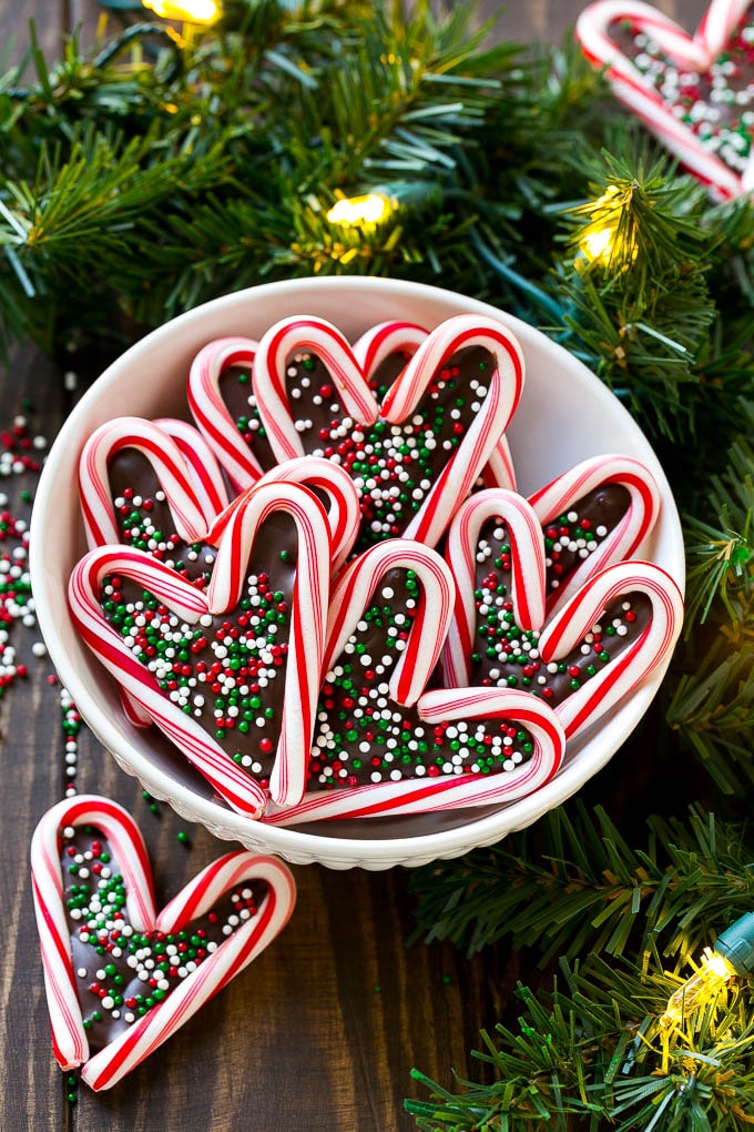 A bowl of candy cane hearts topped with festive sprinkles.