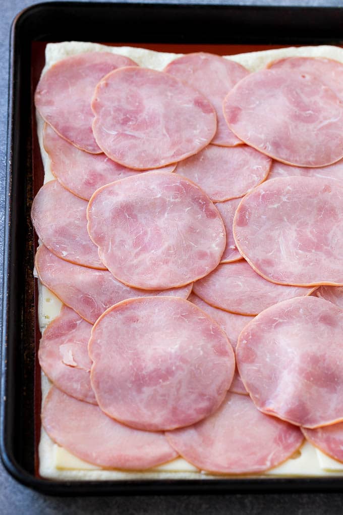Ham and Cheese Pinwheels Recipe | Ham and Cheese Roll Ups | Ham and Cheese Rolls | Ham and Cheese Bread Rolls #ham #cheese #appetizer #pinwheels #jonep Slices of ham and cheese on top of dough.