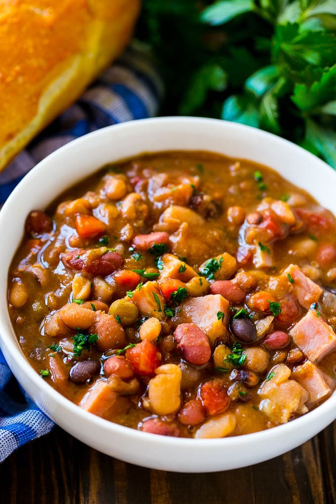 Slow Cooker Ham Bone Soup | Ham and Bean Soup | Ham Bone and Bean Soup | Ham Soup | Leftover Ham Recipe #ham #hamsoup #leftoverham #soup #slowcooker #crockpot #jonep Crock pot ham bone soup in a bowl topped with parsley.
