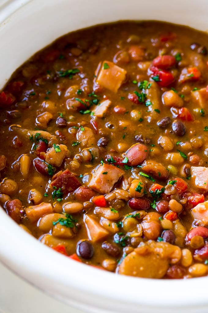 Slow Cooker Ham Bone Soup | Ham and Bean Soup | Ham Bone and Bean Soup | Ham Soup | Leftover Ham Recipe #ham #hamsoup #leftoverham #soup #slowcooker #crockpot #jonep A slow cooker full of soup with parsley on top.