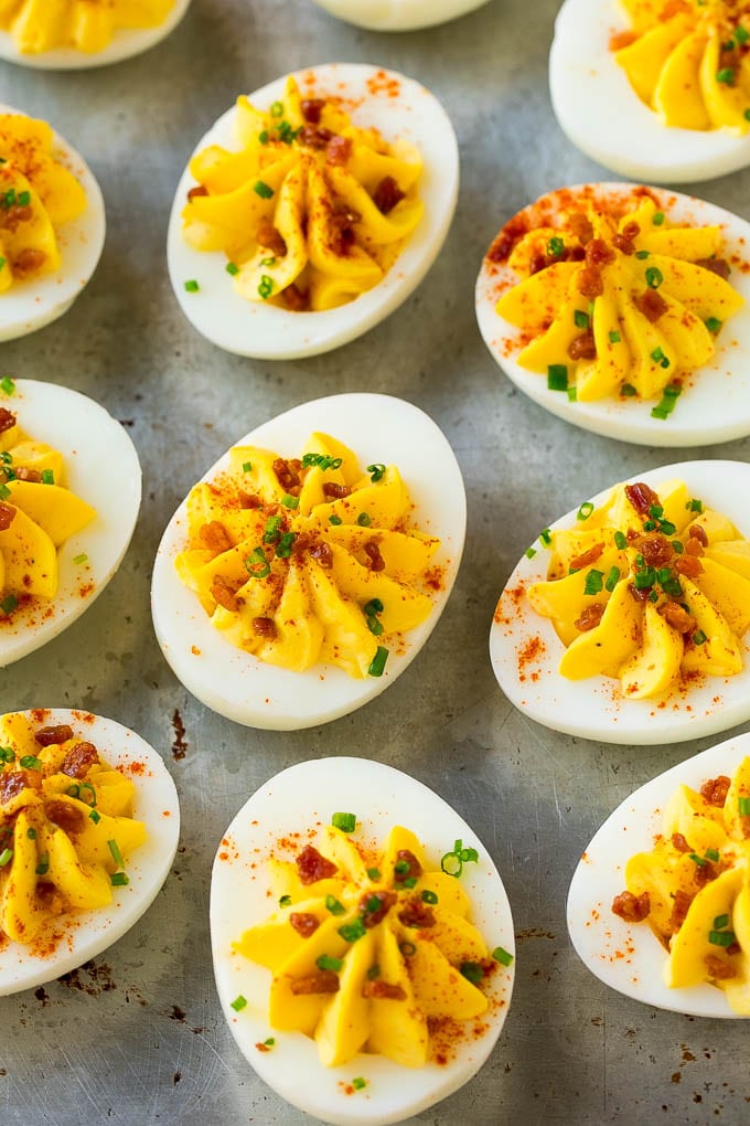 Bacon Deviled Eggs | Deviled Eggs Recipe #eggs #keto #lowcarb #bacon #appetizer #jonep Bacon deviled eggs topped with chives and paprika on a sheet pan.