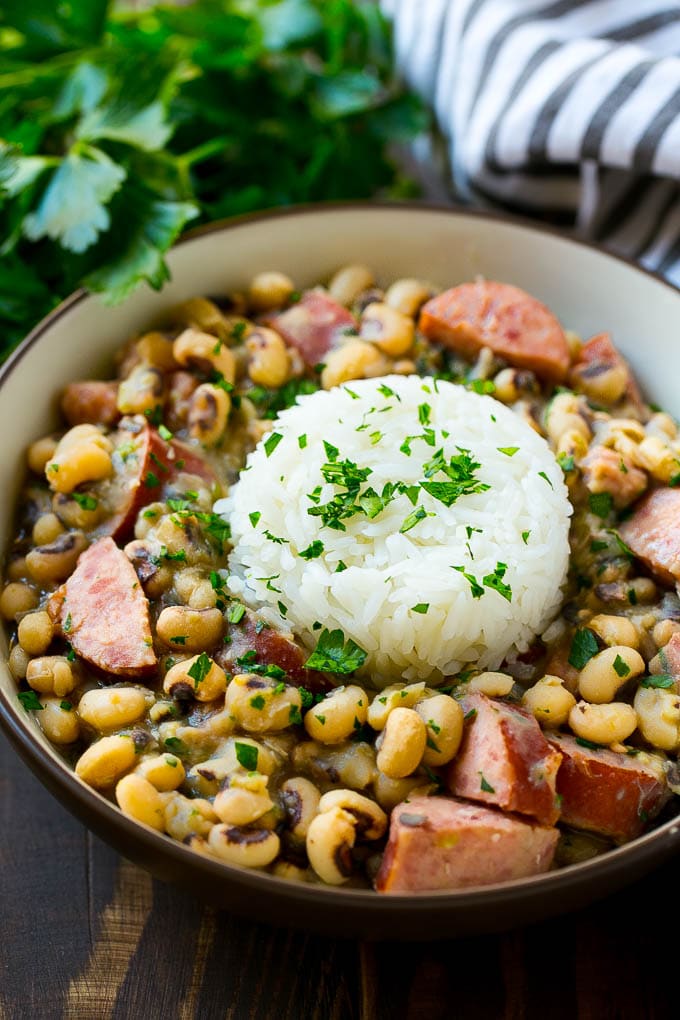 Slow Cooker Black Eyed Peas Recipe | Crock Pot Black Eyed Peas | Southern Black Eyed Peas | Black Eyed Peas with Ham | Black Eyed Peas with Sausage #blackeyedpeas #slowcooker #crockpot #sausage #newyears #dinner #jonep A bowl of slow cooker black eyed peas with a scoop of rice.