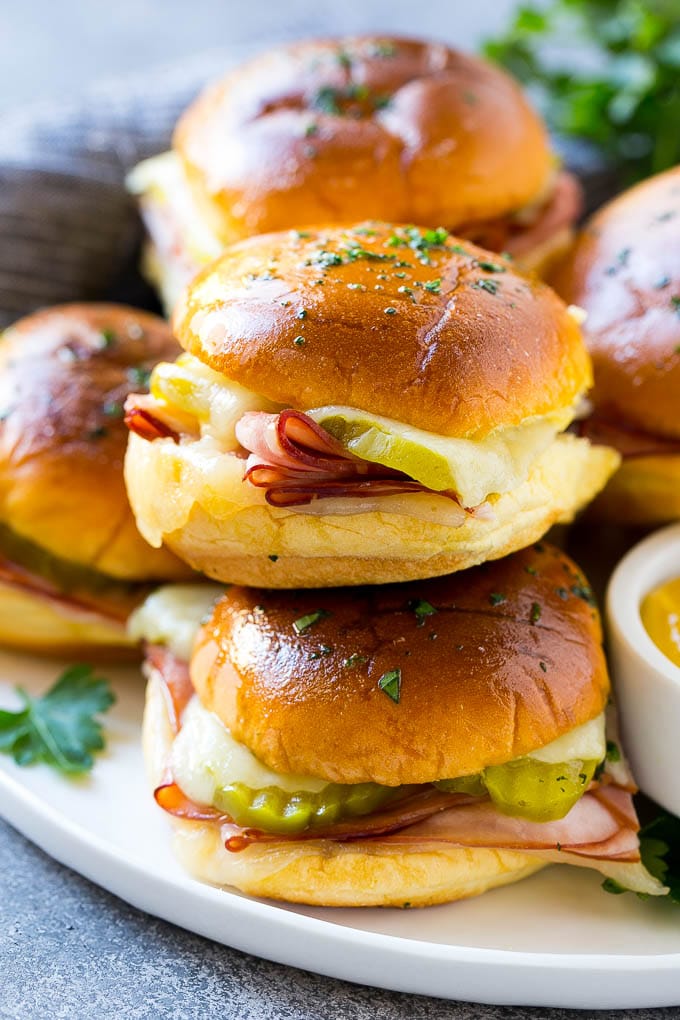 Cuban Sliders Recipe | Cuban Sandwich Recipe | Slider Sandwiches | Ham and Cheese Sliders #sliders #sandwiches #ham #cheese #appetizer #jonep A pile of cuban sliders filled with ham, cheese and pickles.
