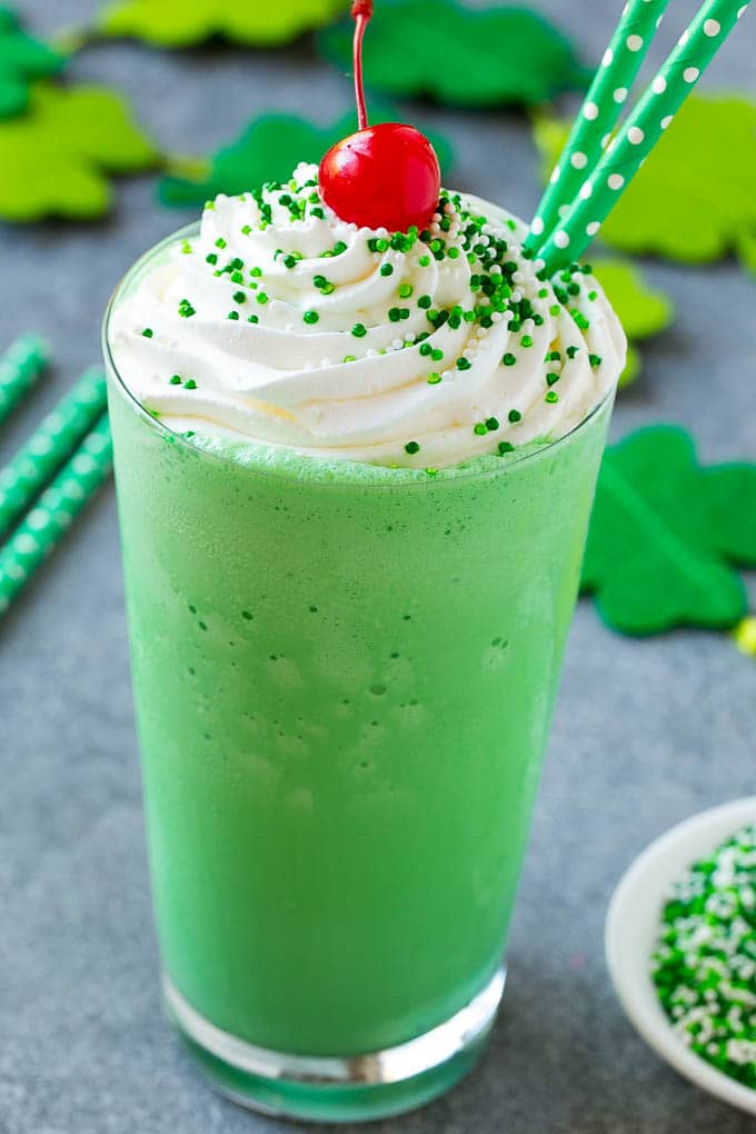 Shamrock Shake Recipe | McDonald's Shamrock Shake | Saint Patrick's Day Drink | Mint Milkshake #milkshake #stpatricksday #saintpatricksday #mint #jonep A glass of shamrock shake topped with whipped cream, sprinkles and a cherry.