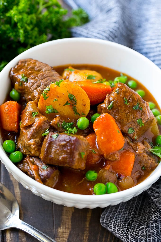 Slow Cooker Beef Stew Recipe | Beef and Potato Stew | Crock Pot Beef Stew | Easy Beef Stew #beef #beefstew #soup #slowcooker #crockpot #dinner #jonep A bowl of slow cooker beef stew with meat, carrots, potatoes and peas.
