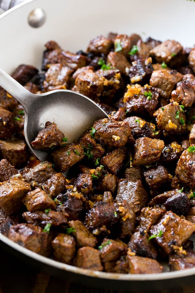 Steak Bites in Garlic Butter Recipe | Garlic Steak | Sirloin Steak Recipe | Steak Appetizer #steak #lowcarb #keto #jonep #dinner A pan of steak bites with a serving spoon.