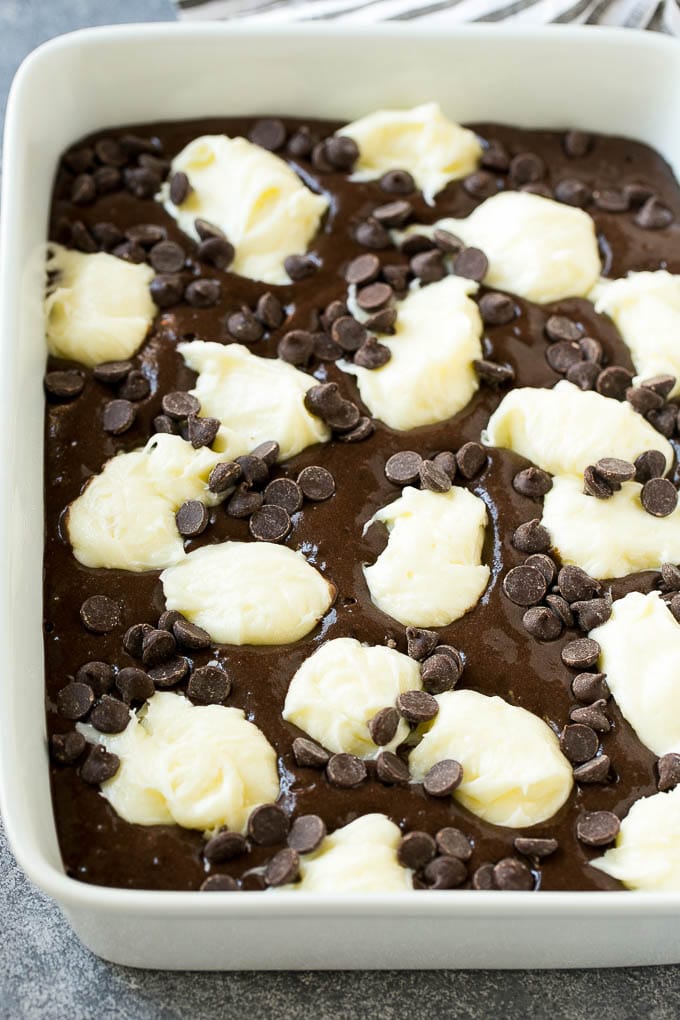 Earthquake Cake Recipe | Chocolate Cake Recipe | Chocolate Coconut Cake | Coconut Pecan Cake #cake #chocolate #coconut #pecans #dessert #chocolatecake #jonep Chocolate cake batter topped with dollops of sweetened cream cheese and chocolate chips.