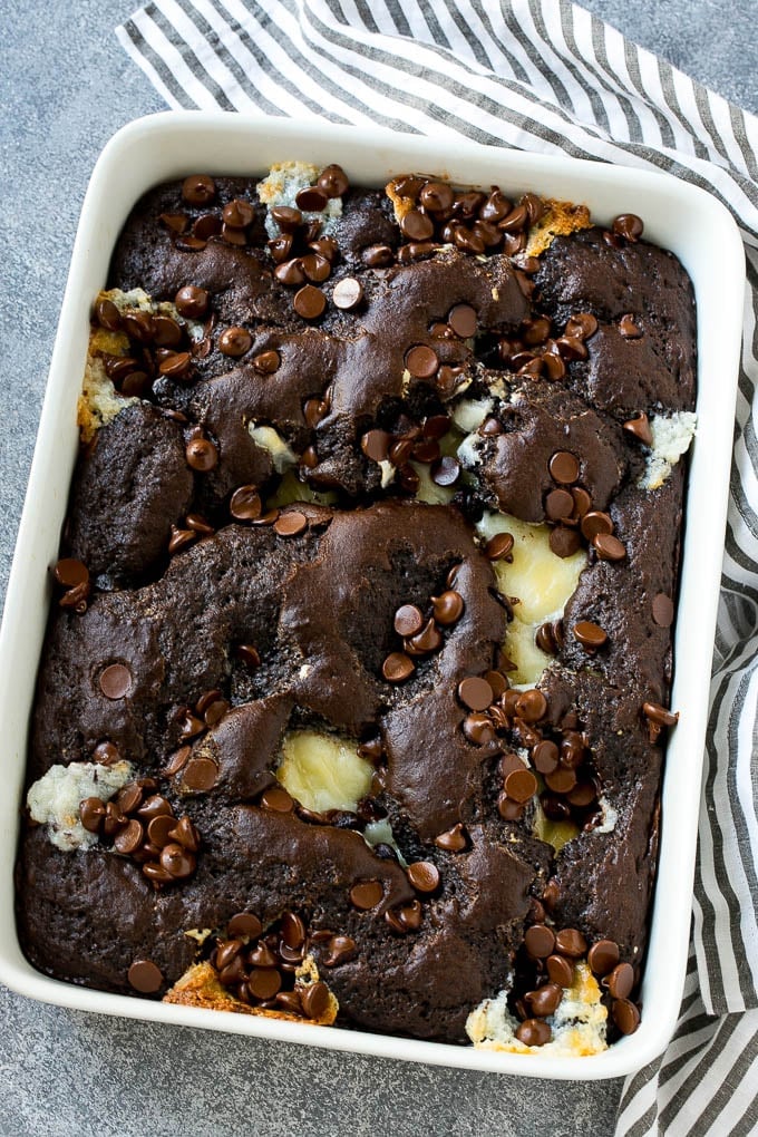 Earthquake Cake Recipe | Chocolate Cake Recipe | Chocolate Coconut Cake | Coconut Pecan Cake #cake #chocolate #coconut #pecans #dessert #chocolatecake #jonep A pan of earthquake cake topped with dollops of cream cheese and chocolate chips.