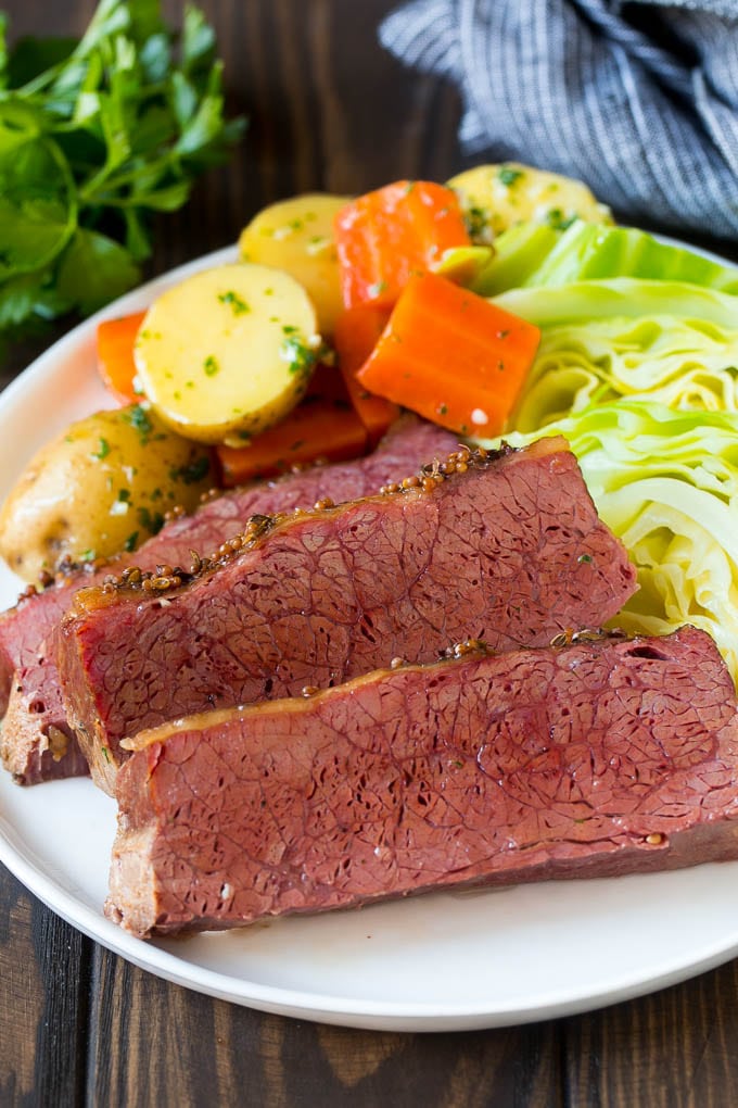 Slow Cooker Corned Beef Recipe | Crock Pot Corned Beef | Corned Beef and Cabbage #beef #cornedbeef #cabbage #potatoes #carrots #stpatricksday #irish #jonep Sliced slow cooker corned beef on a plate with carrots, potatoes and cabbage.