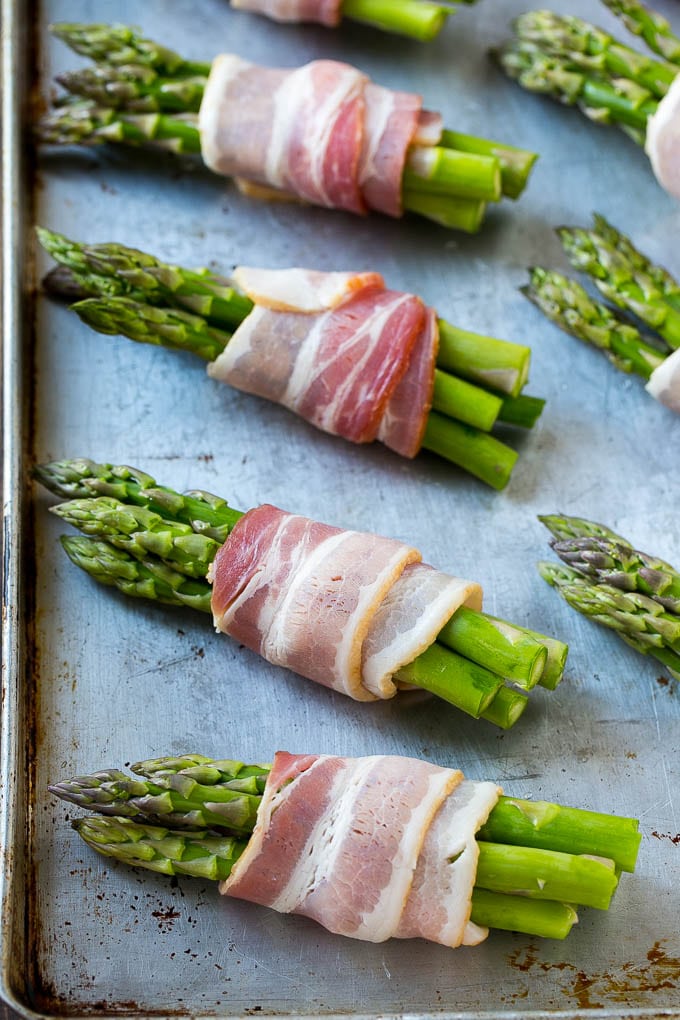Bacon Wrapped Asparagus Recipe | Roasted Asparagus | Asparagus Side Dish #asparagus #bacon #sidedish #dinner #jonep Raw asparagus bundles on a sheet pan.
