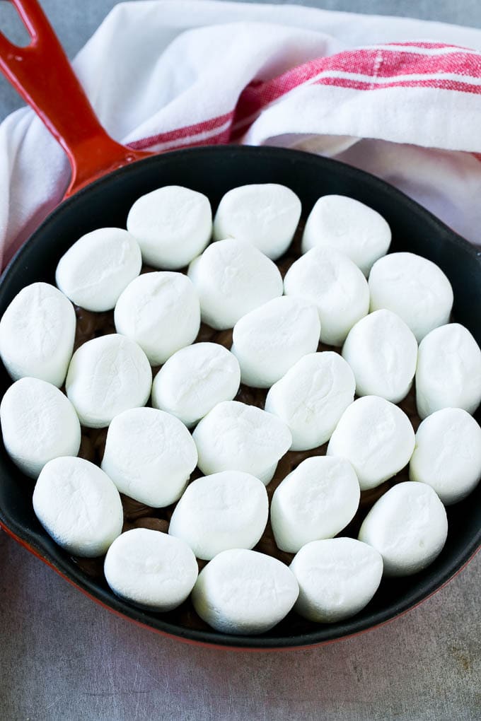 S'mores Dip Recipe | S'mores Skillet | Baked S'mores #smores #dip #chocolate #marshmallow #dessert #jonep A pan of chocolate chips topped with whole marshmallows.