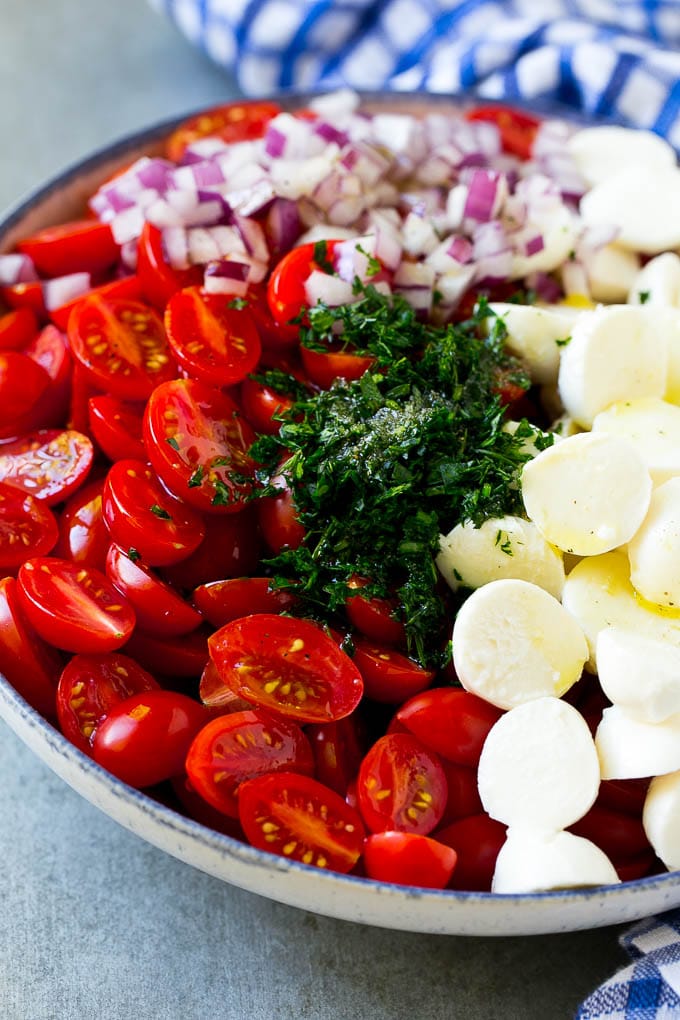 Cherry Tomato Salad Recipe | Tomato Mozzarella Salad | Caprese Salad | Tomato Salad #tomatoes #salad #tomatosalad #caprese #jonep Cherry tomatoes, herbs, mozzarella balls and red onion drizzled with dressing in a bowl.
